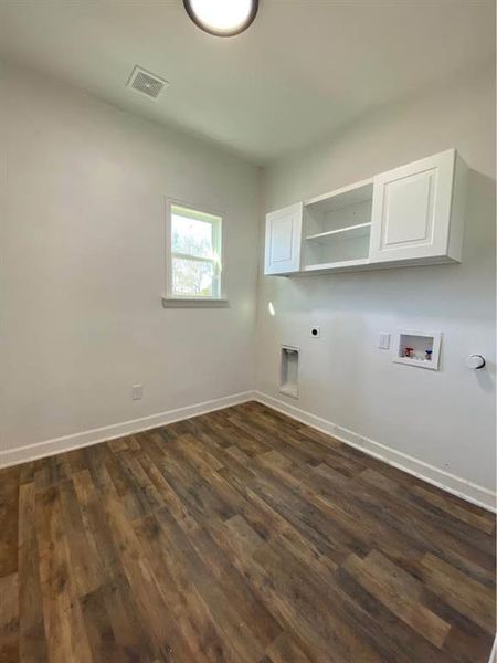 Laundry room featuring electric dryer hookup, cabinets, hookup for a washing machine, and dark wood-type flooring