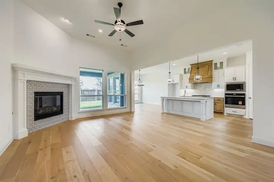 Unfurnished living room featuring recessed lighting, light wood-style flooring, a fireplace, a ceiling fan, and a chandelier
