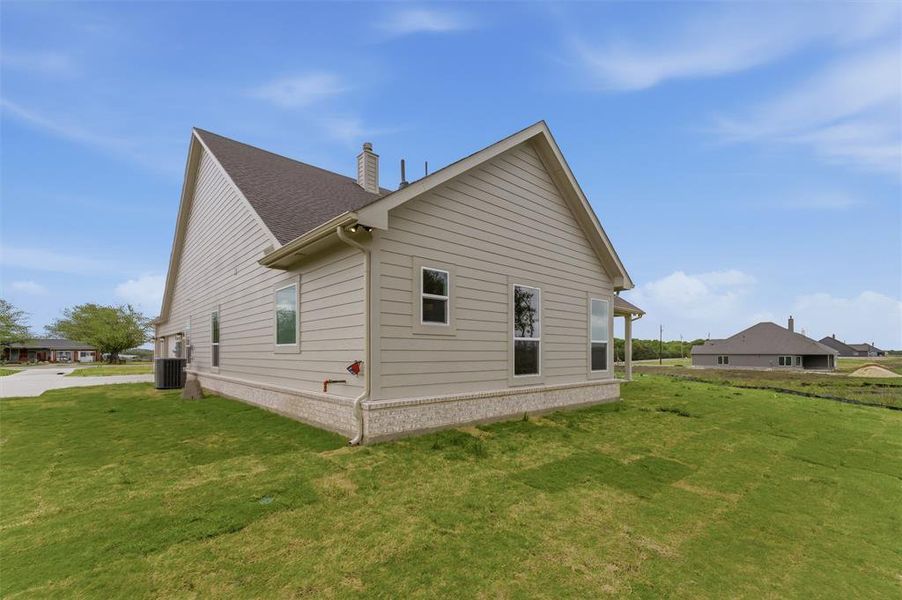 View of side of home featuring a lawn and a chimney