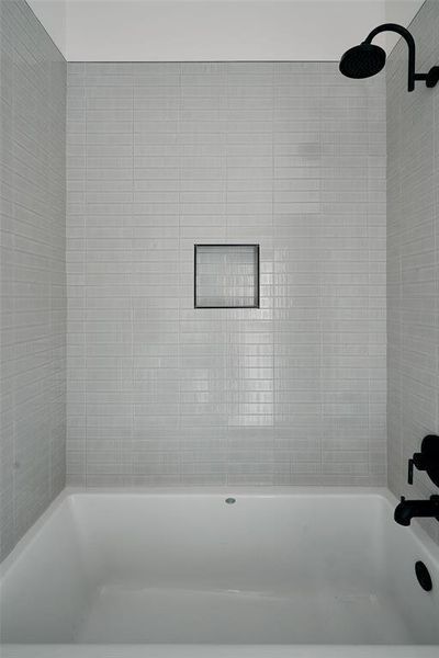Bathtub featuring light-toned subway tile surround, matte black shower fixtures, and a recessed shower niche Bathtub featuring light-toned subway tile surround, matte black shower fixtures, and a recessed shower niche