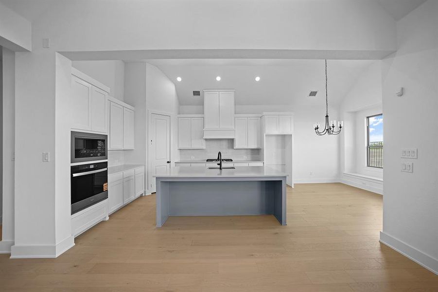 Kitchen featuring lofted ceiling, white cabinets, tasteful backsplash, a breakfast bar area, and stainless steel oven