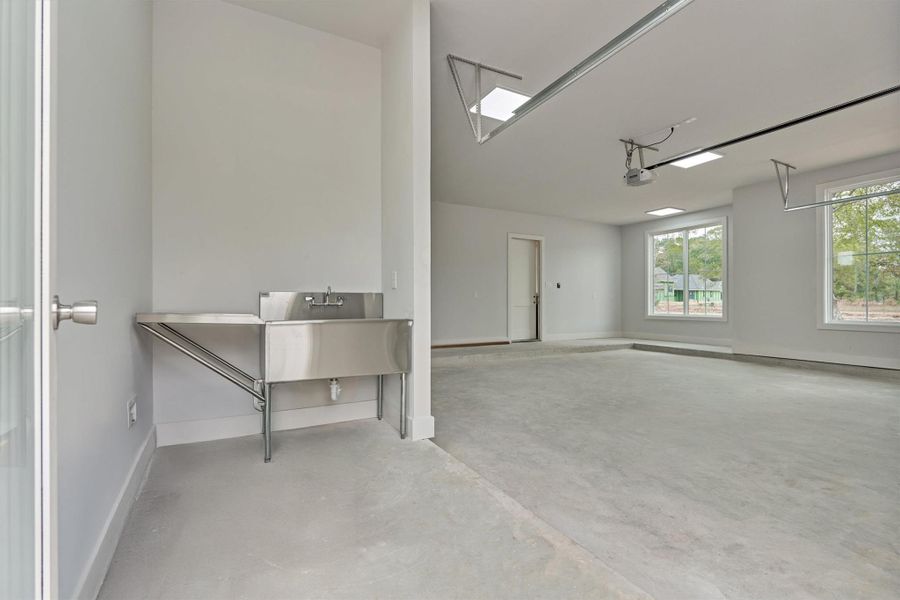 Garage utility zone with a stainless steel wash sink—perfect for projects, pets, and easy cleanup, all within a bright, spacious three-car garage.