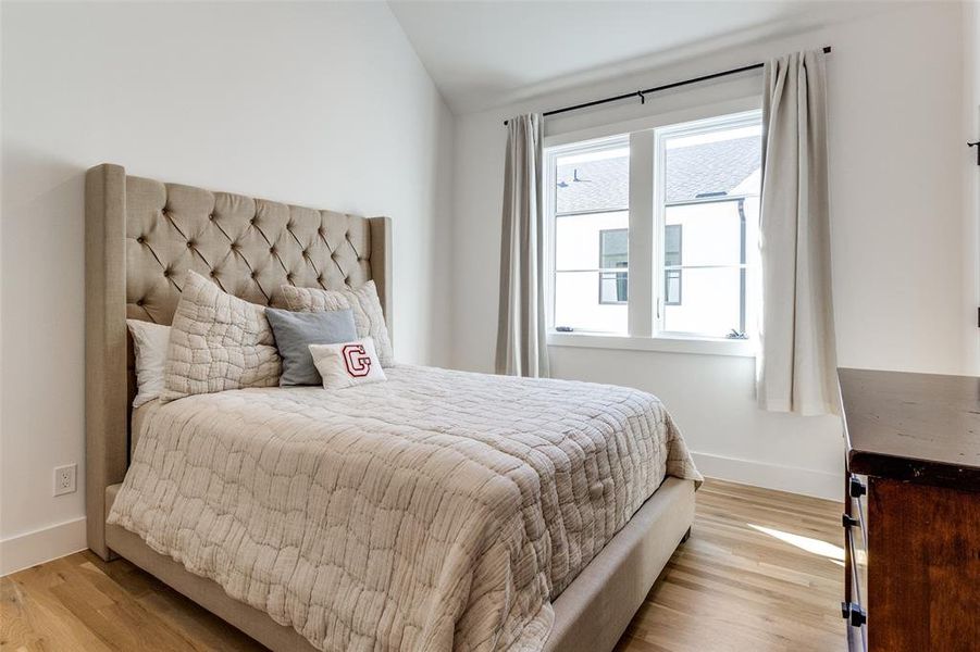 Bedroom featuring light wood-style floors and lofted ceiling Bedroom featuring light wood-style floors and lofted ceiling