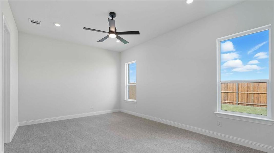 Carpeted interior space featuring white walls and a contemporary black ceiling fan