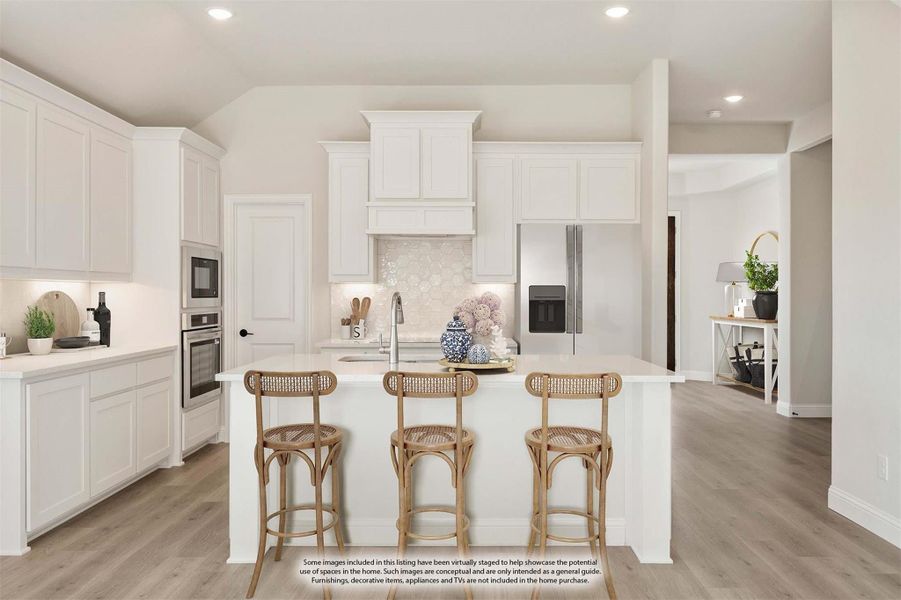 Kitchen with white cabinets, center island with three rattan bar stools, stainless steel appliances, and light wood floors