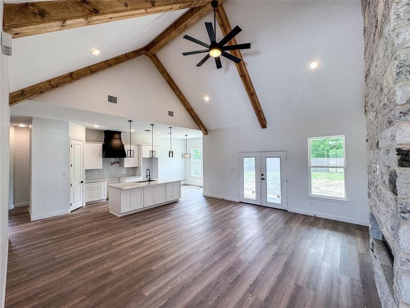 Unfurnished living room with a sink, high vaulted ceiling, beam ceiling, baseboards, and ceiling fan Unfurnished living room with a sink, high vaulted ceiling, beam ceiling, baseboards, and ceiling fan