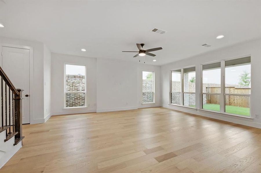 Spacious interior with light wood-finish flooring, recessed lighting, and a dark-toned ceiling fan Spacious interior with light wood-finish flooring, recessed lighting, and a dark-toned ceiling fan