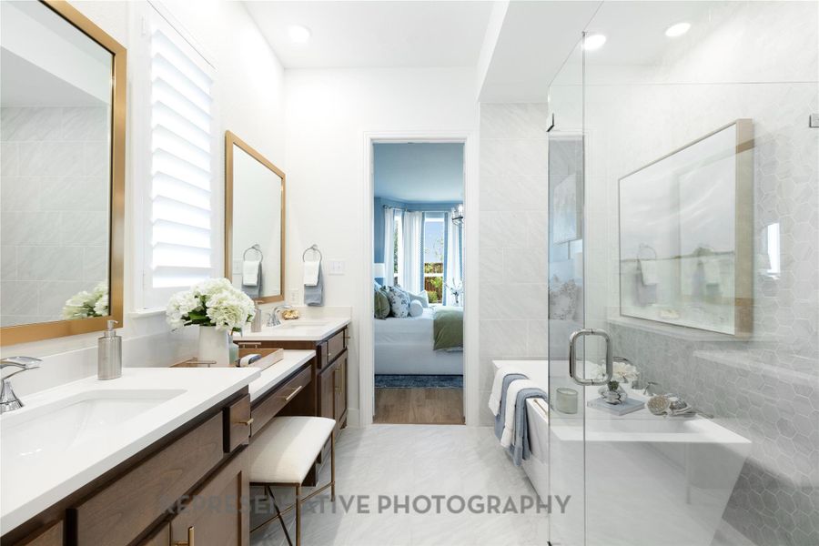 Ensuite bathroom with two vanities, a bath, a stall shower, and tile walls
