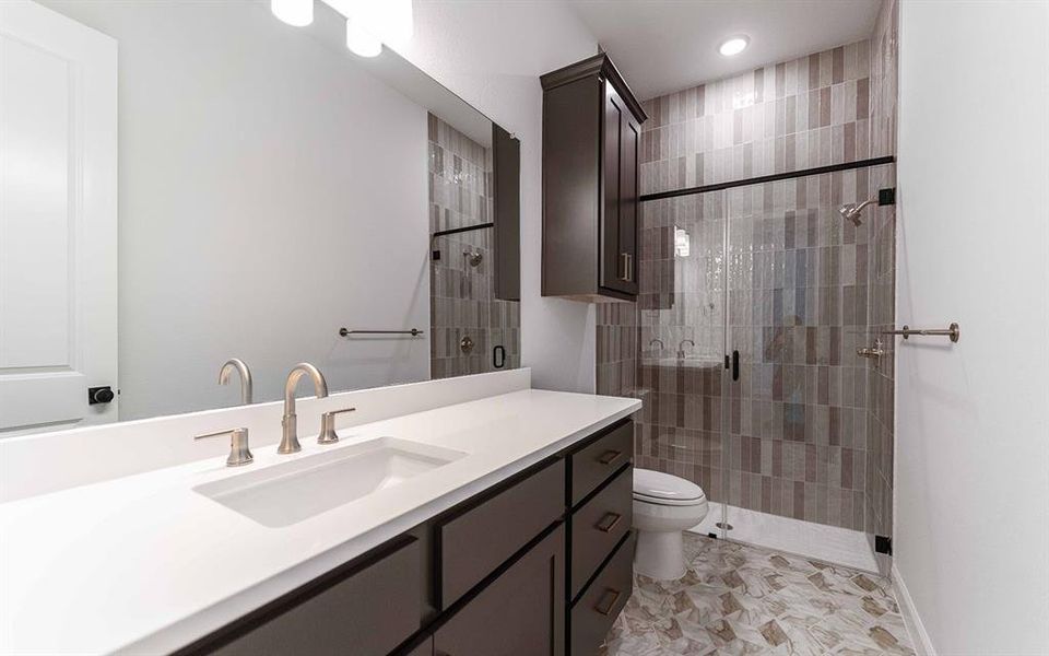 Contemporary bathroom featuring a dark wood-finish vanity with an integrated sink and brushed nickel faucet, a spacious mirror, and a tiled shower with a glass enclosure Contemporary bathroom featuring a dark wood-finish vanity with an integrated sink and brushed nickel faucet, a spacious mirror, and a tiled shower with a glass enclosure