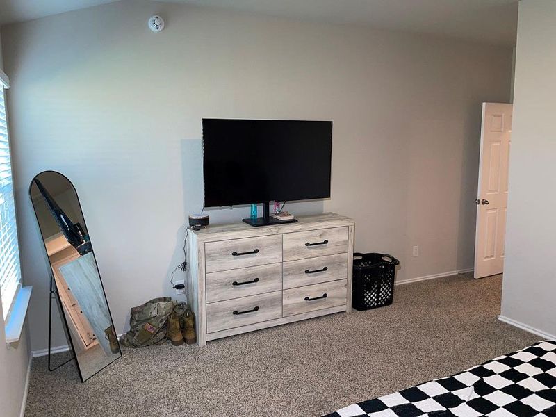 Carpeted bedroom featuring baseboards and vaulted ceiling