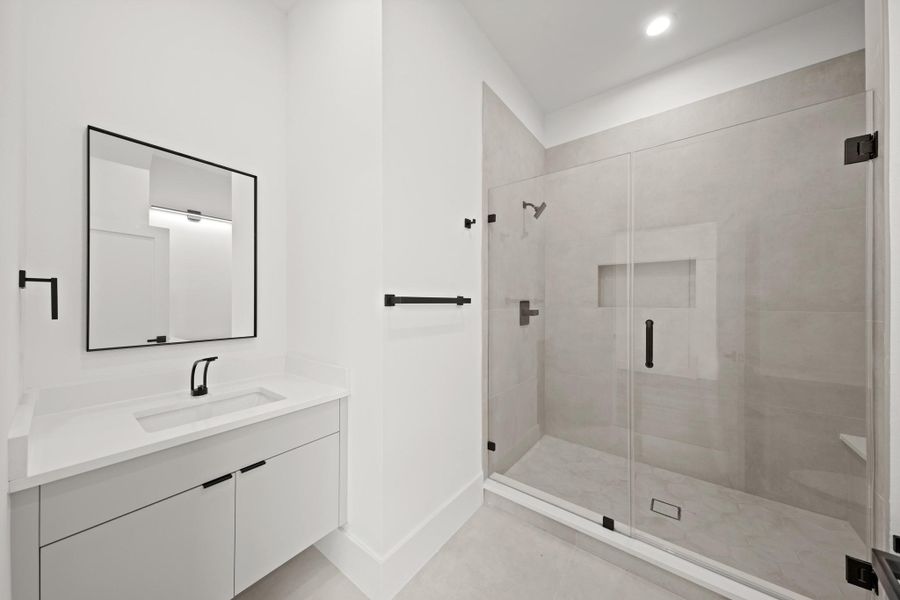 Bright and cheery, the private bath includes a Quartz counter with an undermount sink and a black framed mirror. The beautiful walk-in shower has tile surrounded walls and floors, as well as a built-in niche for soap and shampoo.