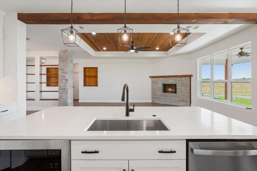 A well-lit kitchen island offers a sophisticated sink and sleek appliances, perfectly complementing the inviting living area beyond.