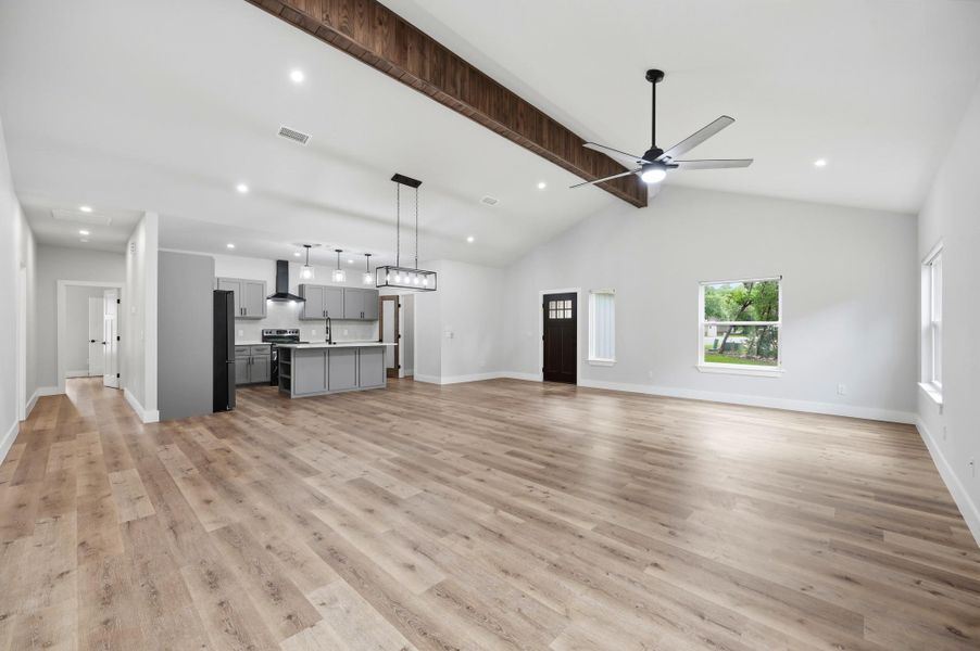 Natural light illuminates the wide-plank flooring, leading to a sleek kitchen with a spacious island. Natural light illuminates the wide-plank flooring, leading to a sleek kitchen with a spacious island.