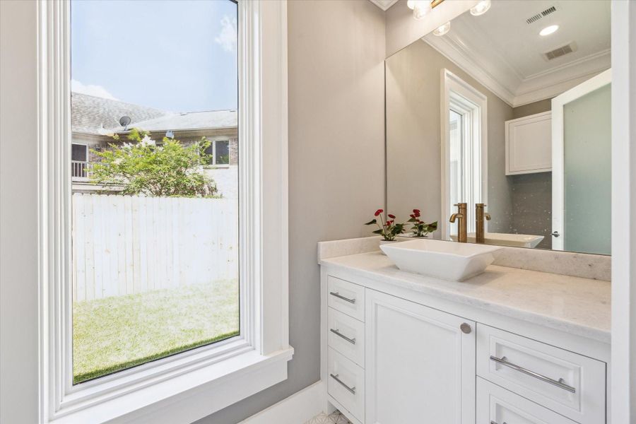 This first floor powder room features a modern vanity with a sleek vessel sink and stylish gold fixtures.
