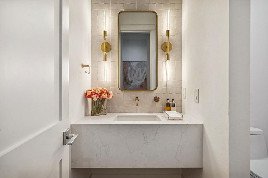 Powder Room with a Floating Quartz Counter, Quartz Skirt Front, White Rectangle Undermount Sink, Wall Mounted Faucet in Champagne Bronze Finish, Tile Backsplash, Satin Brass Mirror and 2 Light 4-3/4" Wide Wall Sconce in Aged Brass.