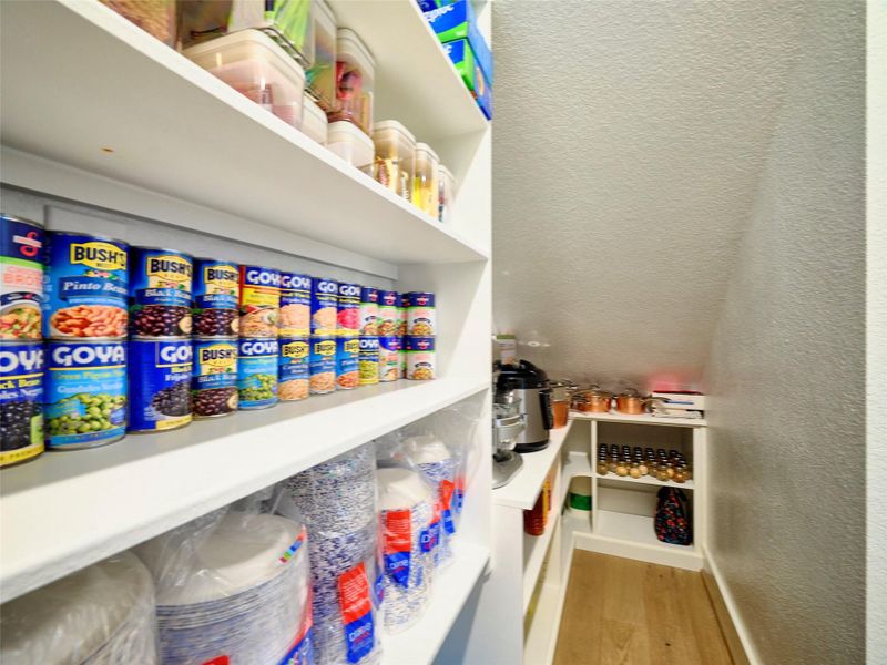 Experience efficient storage in this spacious pantry, featuring custom, neatly organized shelving for easy access and tidiness.