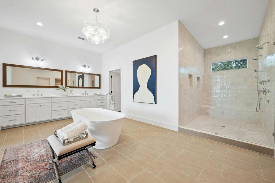 Also featuring an oversized contemporary dual vanity with quartz countertop and Shaker-style cabinetry along with a private commode, two custom walk-in closets, and a decadent walk-in shower.