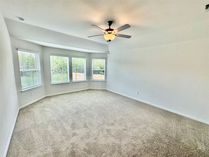 Carpeted empty room featuring plenty of natural light, a textured ceiling, and a ceiling fan Carpeted empty room featuring plenty of natural light, a textured ceiling, and a ceiling fan