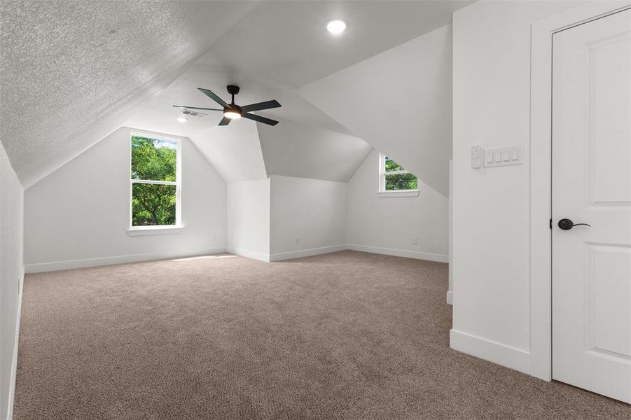 This spacious room features neutral-toned carpeting and bright white walls, complemented by a white door with a black handle