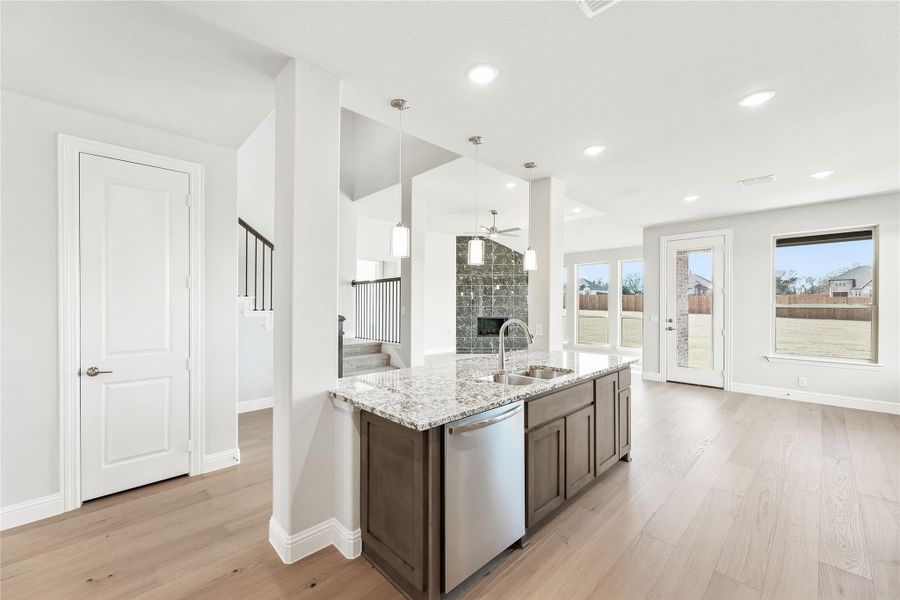 Kitchen island with granite countertop, dark cabinets, and stainless steel dishwasher, open to living area with hardwood floors Kitchen island with granite countertop, dark cabinets, and stainless steel dishwasher, open to living area with hardwood floors