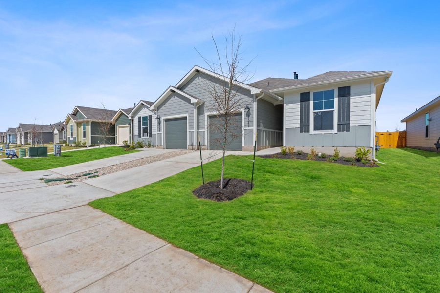 View of front of home featuring a garage, concrete driveway, fence, and a front lawn