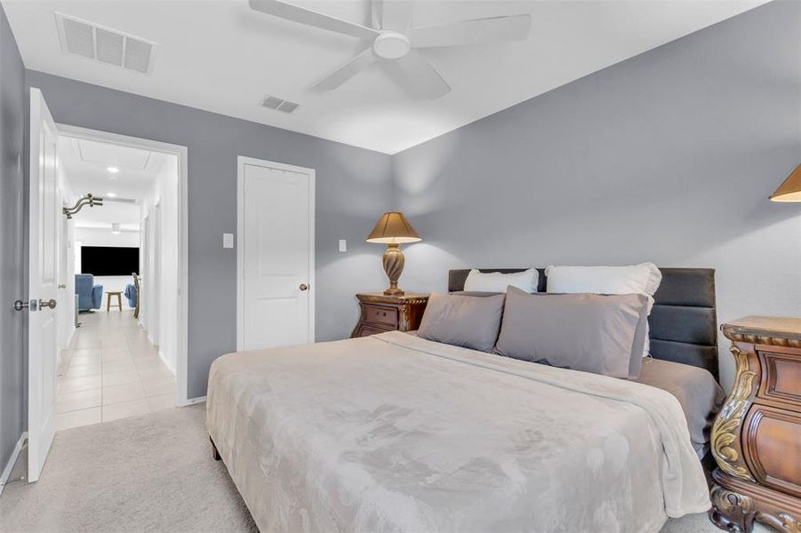 Bedroom featuring light carpet, attic access, ceiling fan, and light tile patterned flooring