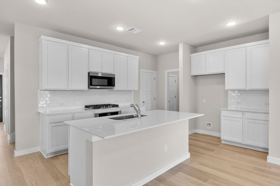 A well-appointed kitchen features a central island, gas range, and extensive white cabinetry. A well-appointed kitchen features a central island, gas range, and extensive white cabinetry.