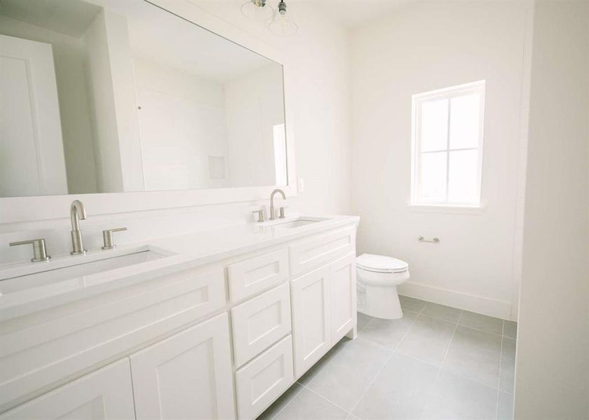 Bathroom featuring dual bowl vanity, tile flooring, and toilet