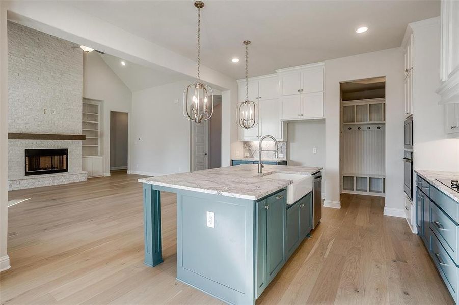 Kitchen featuring built in shelves, a center island with sink, white cabinetry, and sink