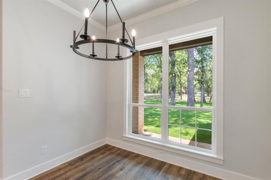 Unfurnished dining area with an inviting chandelier, dark hardwood / wood-style flooring, and ornamental molding