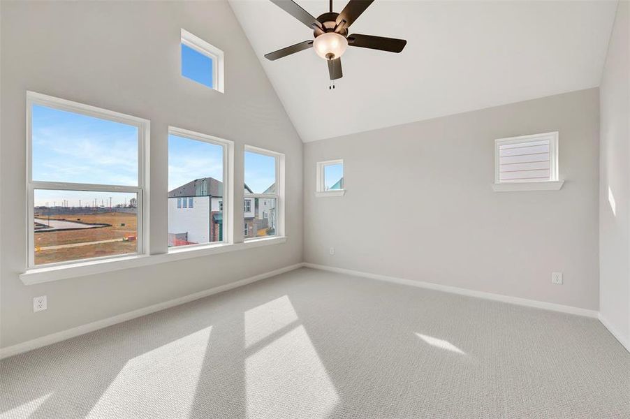 Empty room featuring carpet, a ceiling fan, and vaulted ceiling