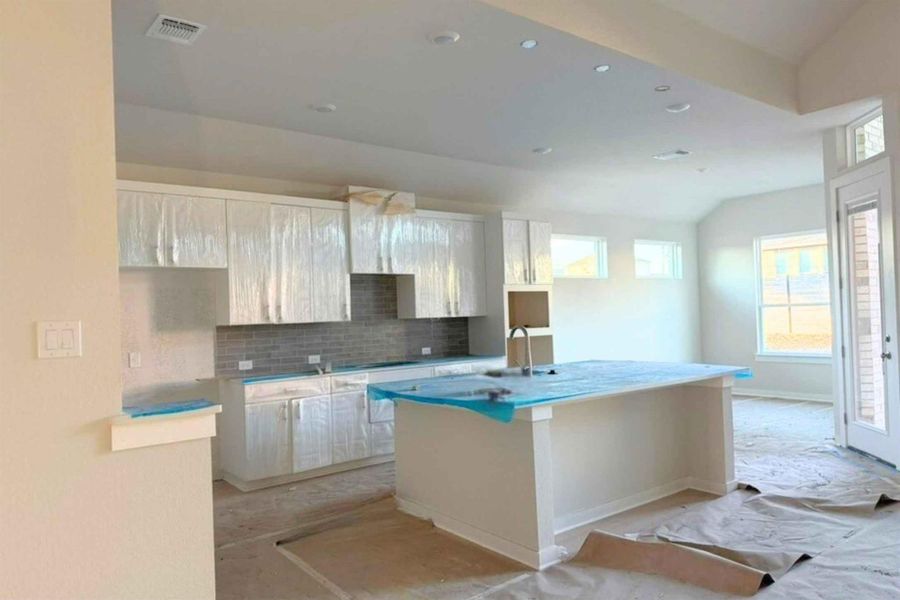Kitchen featuring vaulted ceiling, backsplash, recessed lighting, a kitchen island with sink, and a kitchen breakfast bar