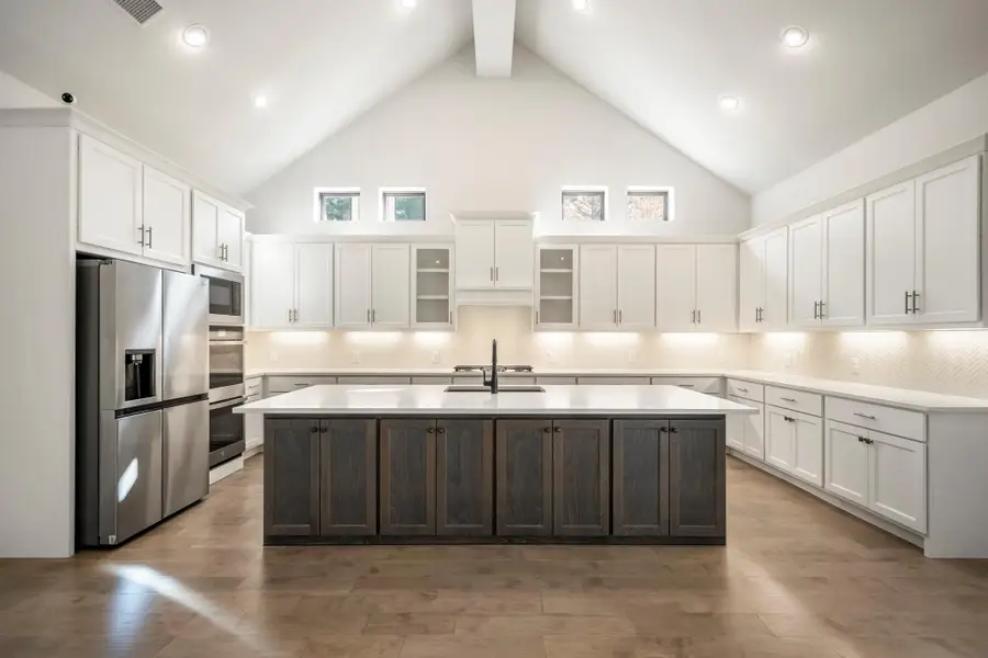 High vaulted ceilings, ample natural light, and a large island with a dark wood finish.