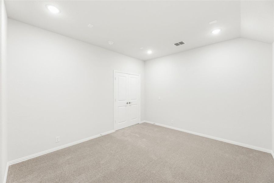 Empty bedroom with beige carpet, white walls, recessed lighting, and a double closet door Empty bedroom with beige carpet, white walls, recessed lighting, and a double closet door