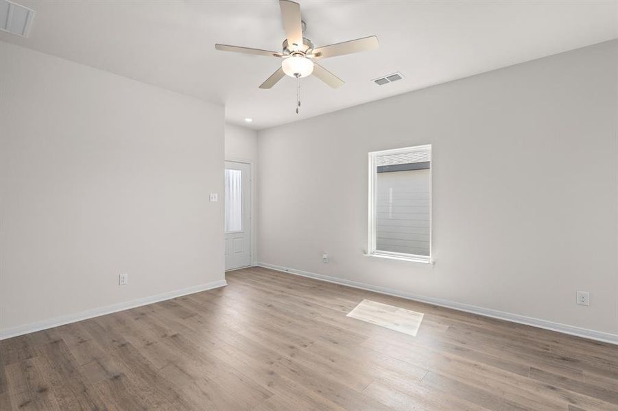 Empty room featuring wood finished floors, healthy amount of natural light, and ceiling fan