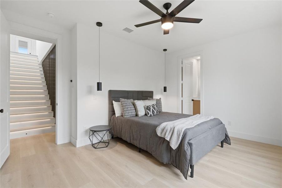 Bedroom featuring light wood-finish flooring, a contemporary ceiling fan, and modern pendant lighting Bedroom featuring light wood-finish flooring, a contemporary ceiling fan, and modern pendant lighting