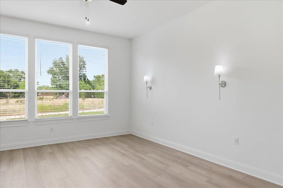 A tranquil primary bedroom with ample light and versatile hardwood-style flooring. A tranquil primary bedroom with ample light and versatile hardwood-style flooring.