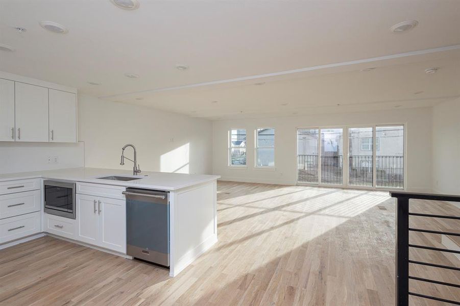 Kitchen with a peninsula, a sink, open floor plan, stainless steel dishwasher, and built in microwave