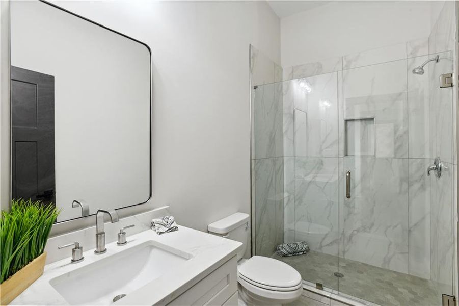 Bathroom with toilet, an enclosed shower, and vanity