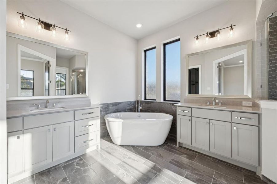 Large bathtub between vanities in primary bathroom.