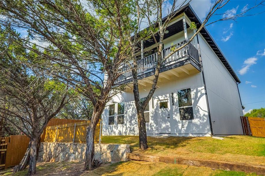 Back of house featuring a balcony, a fenced backyard, and a patio