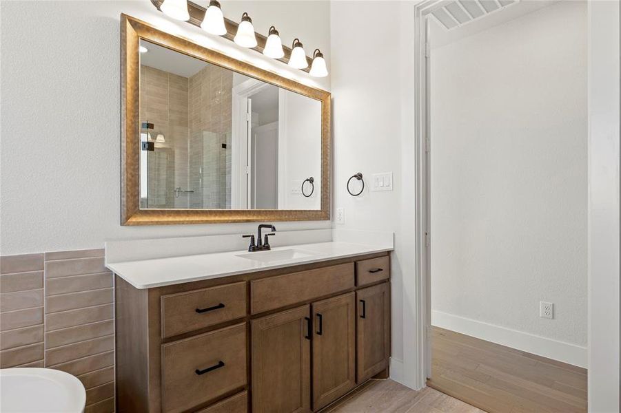 Bathroom featuring vanity, wood-type flooring, and a tile shower