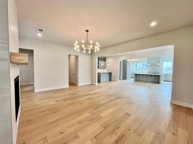 Unfurnished living room with light wood-type flooring, a fireplace, and a chandelier