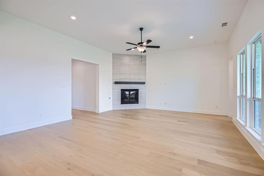 Unfurnished living room featuring light wood-style flooring, healthy amount of natural light, ceiling fan, baseboards, and recessed lighting Unfurnished living room featuring light wood-style flooring, healthy amount of natural light, ceiling fan, baseboards, and recessed lighting