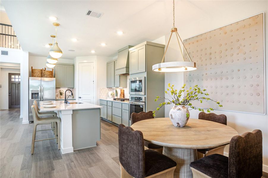 This bright, modern kitchen features stainless steel appliances, a large island with bar seating, and elegant pendant lighting. Adjacent is a cozy dining area with a round table and stylish chandelier, perfect for family meals. This bright, modern kitchen features stainless steel appliances, a large island with bar seating, and elegant pendant lighting. Adjacent is a cozy dining area with a round table and stylish chandelier, perfect for family meals.