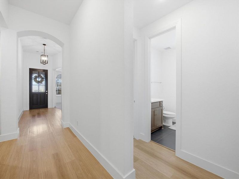 Hallway featuring arched walkways and light wood-style floors