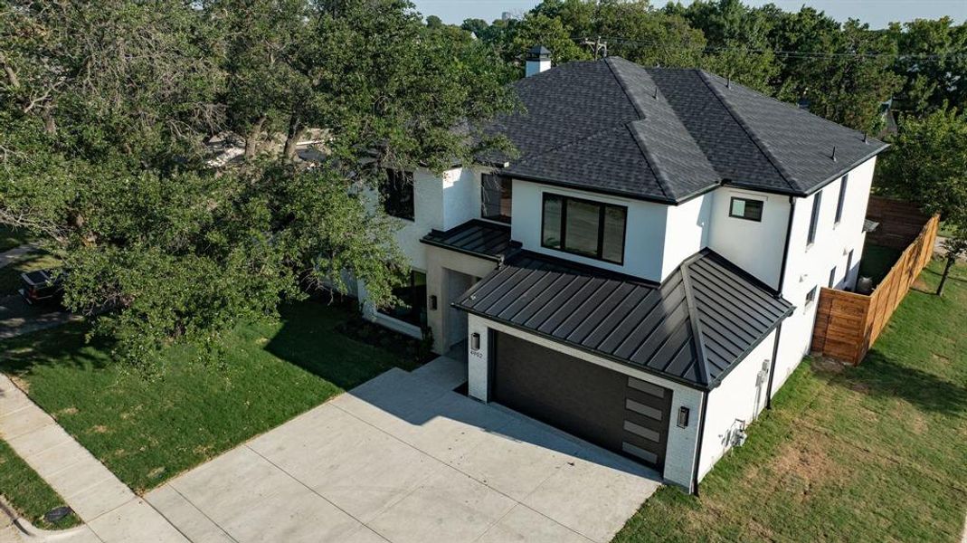 View of front of home featuring a standing seam roof, a front yard, a metal roof, driveway, and stucco siding View of front of home featuring a standing seam roof, a front yard, a metal roof, driveway, and stucco siding