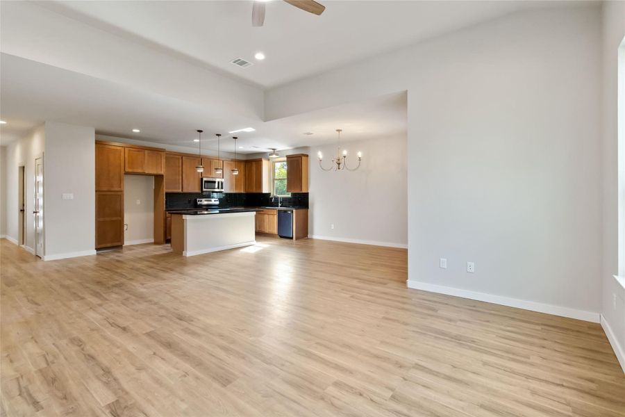 Kitchen featuring open floor plan, dark countertops, a chandelier, light wood finished floors, and recessed lighting Kitchen featuring open floor plan, dark countertops, a chandelier, light wood finished floors, and recessed lighting