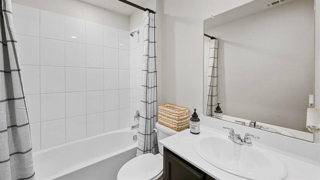 Bathroom featuring a white tiled shower and bathtub, a vanity with an integrated sink, and a large mirror