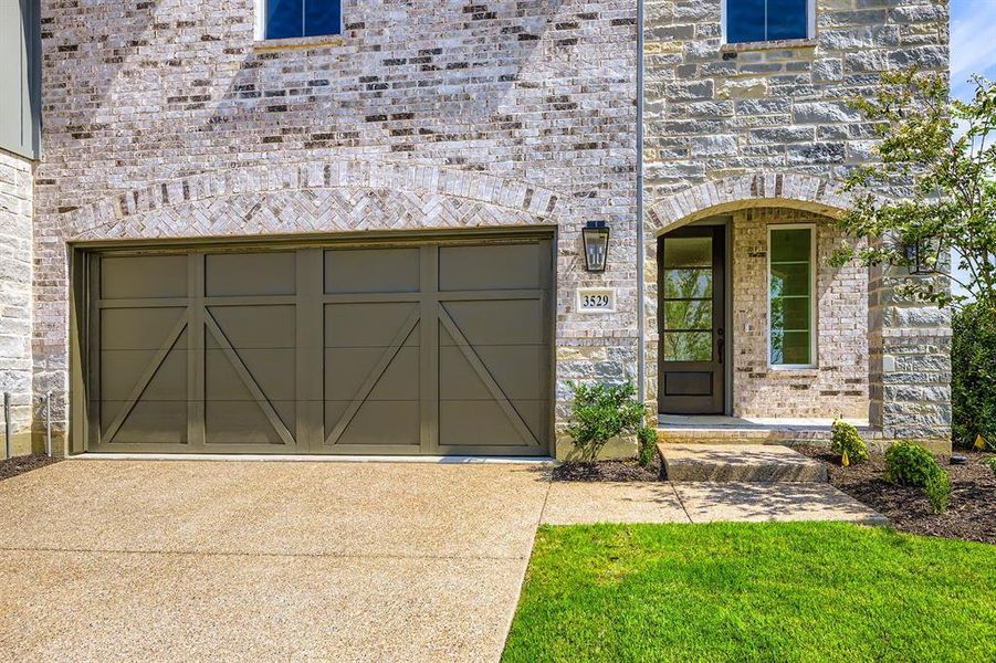 Property entrance with concrete driveway, stone siding, and brick siding